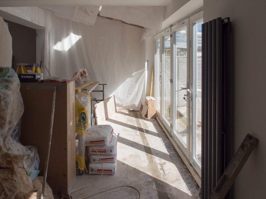 The image depicts an interior space, likely an extension or conservatory, undergoing refurbishment or clearing. On the left side, there are several large bags of construction debris, filled with insul